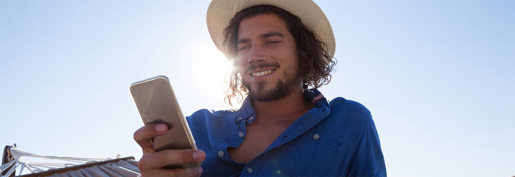 młody meżczyzna w kapeluszu z komórka