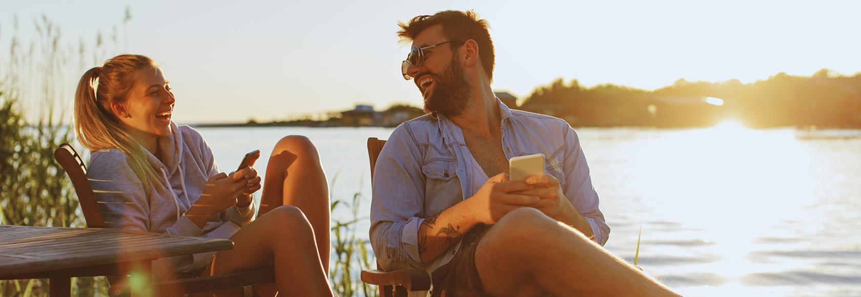 para na leżakach nad jeziorem z komorkami i uśmiechami