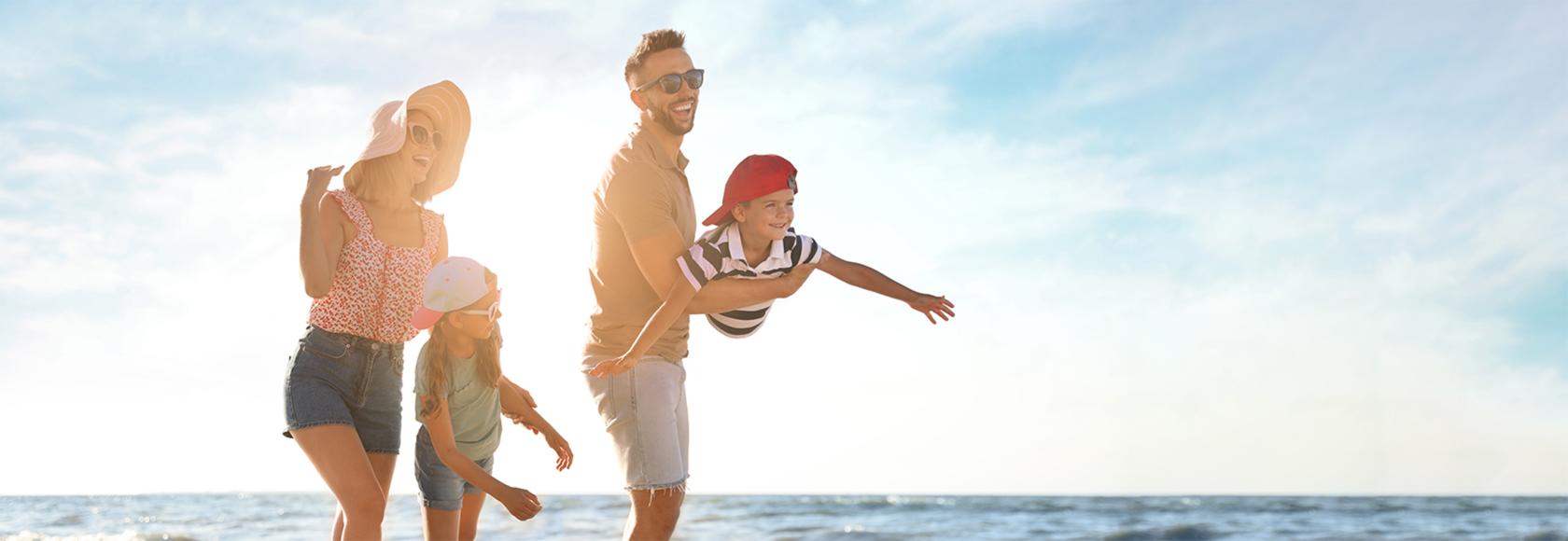 rodzina na plazy, rodzice, dwoje dzieci, chłopca ojciec trzyma na rękach w pozycji samolotu