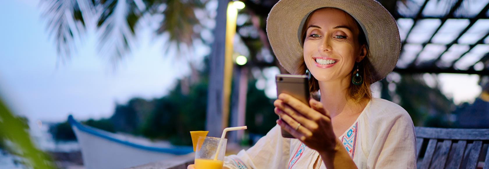 Kobieta w słomianym kapeluszu z sokiem ponarańczowym w tle palmy