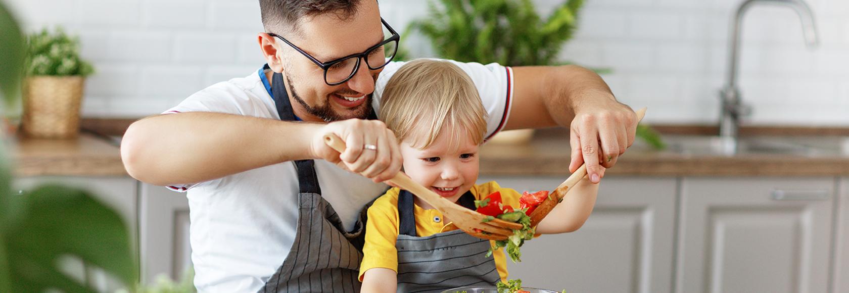 Tata z dzieckiem w kuchni robi sałatkę