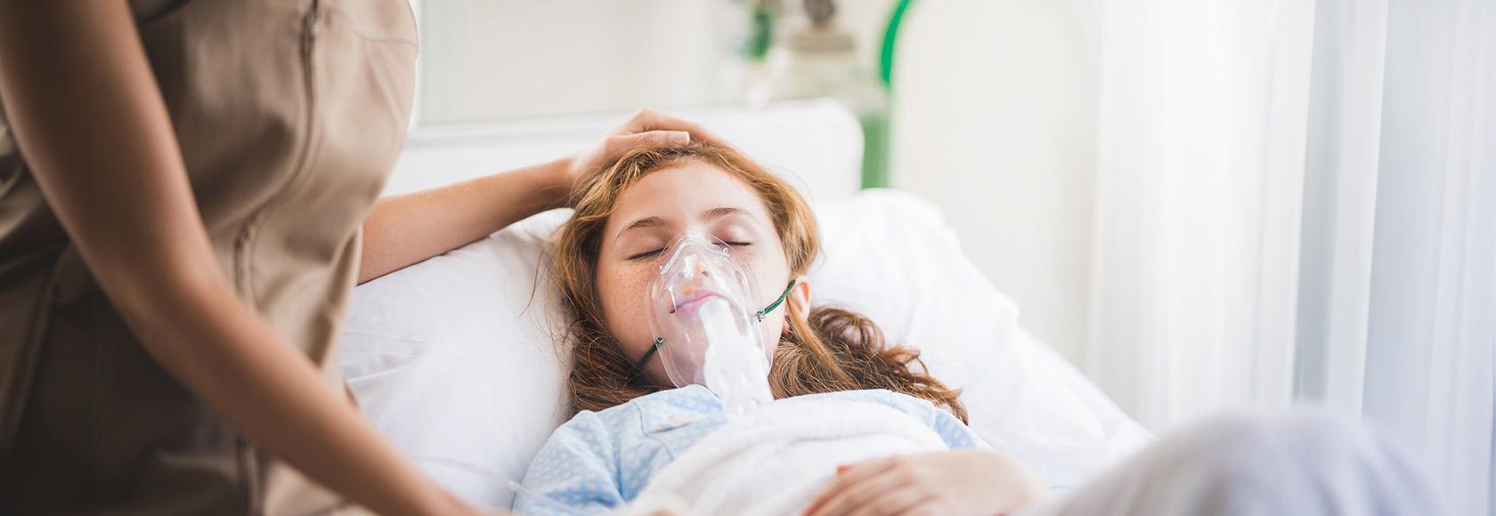 Dziewczynka leży w łóżku w masce tlenowej