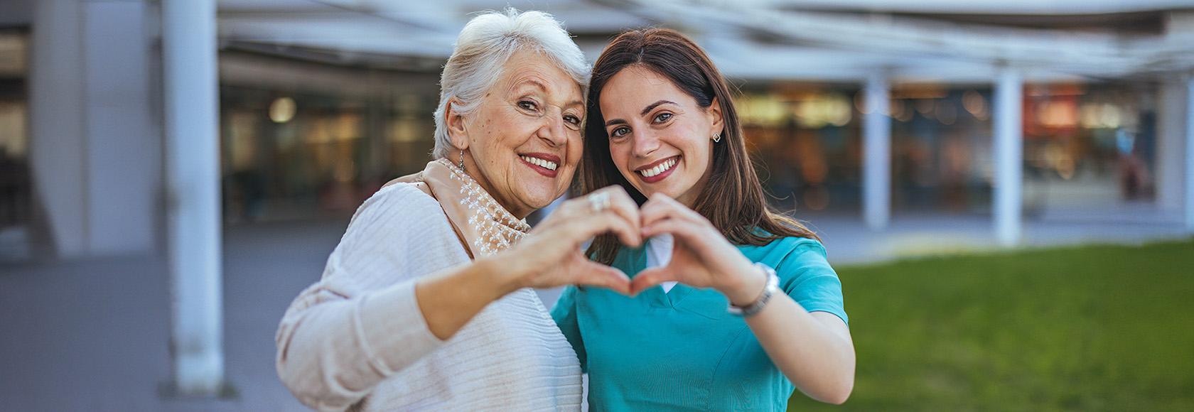 Dwie kobiety w różnym wieku pokazują znak serca