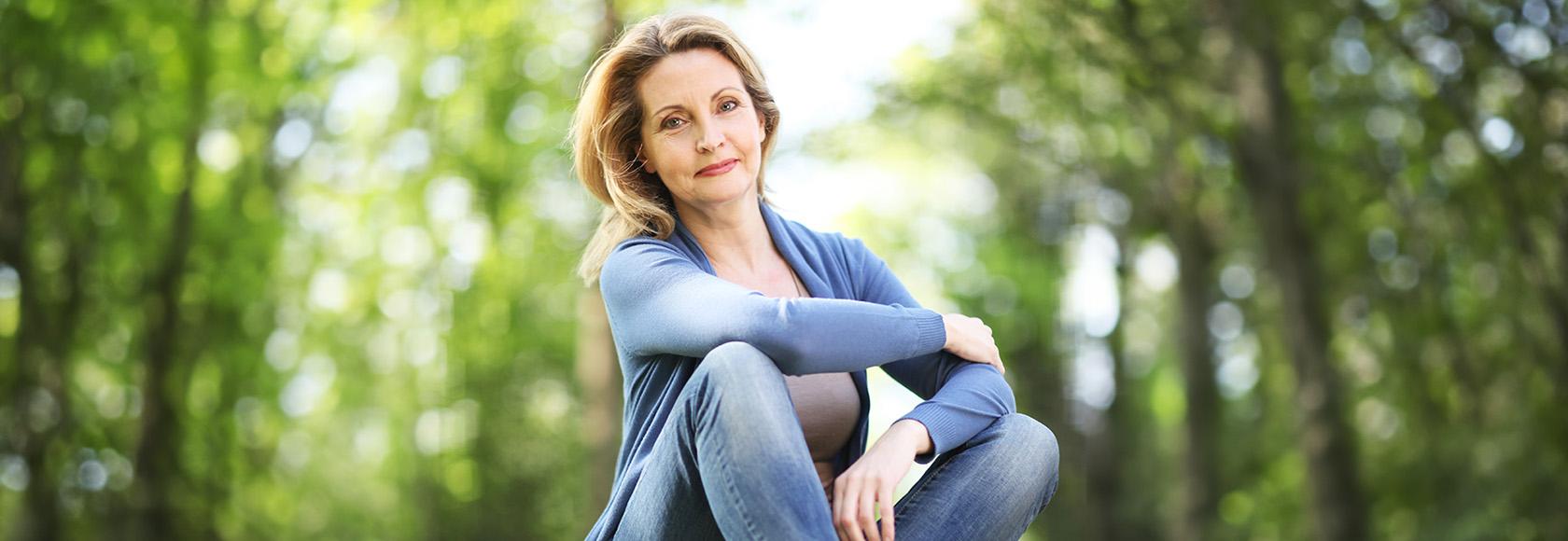 Kobieta siedzi na trawie w lesie