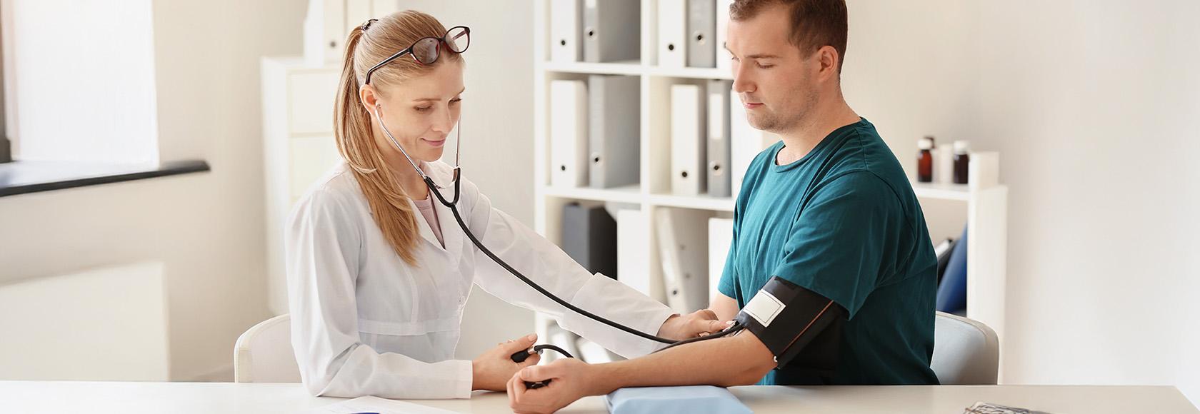 Lekarka mierzy ciśnienie krwi młodemu mężczyźnie