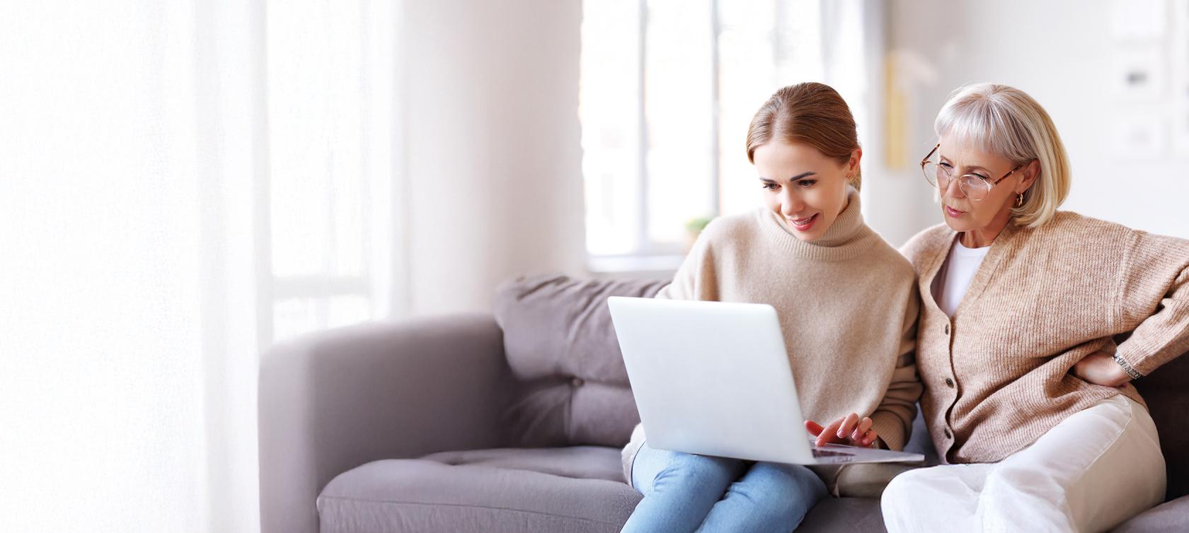 Młodsza kobieta pokazuje starszej coś na komputerze - baner na główną