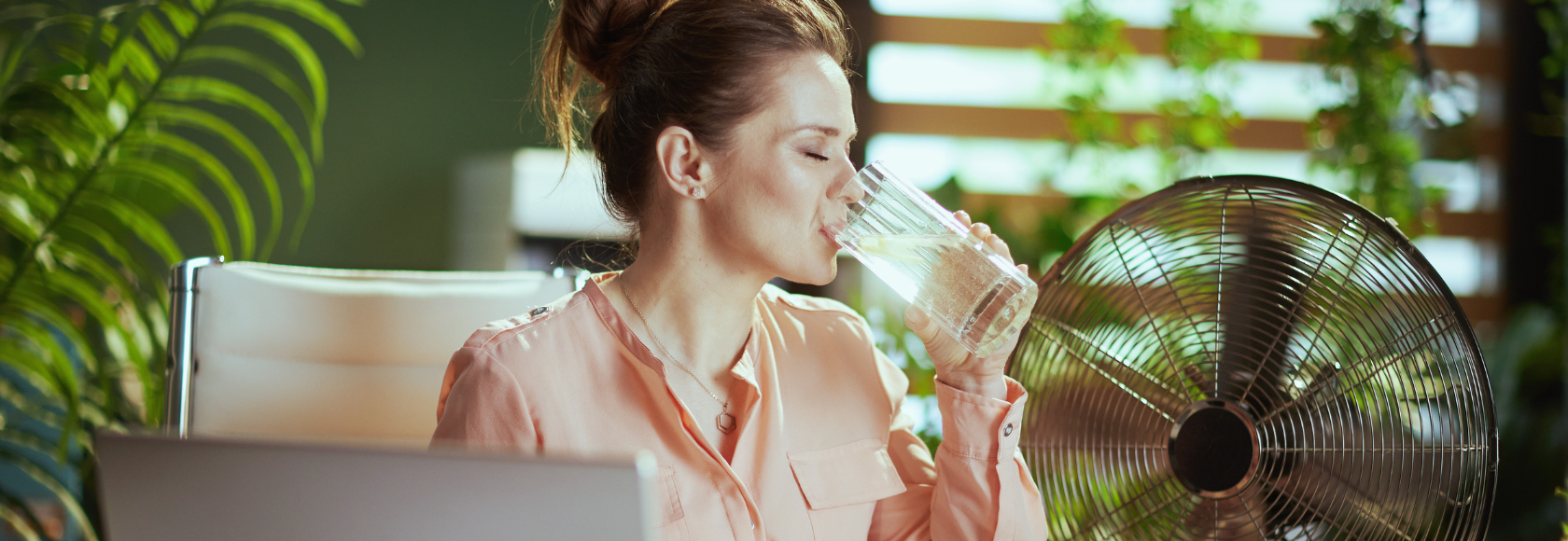 KObieta pije wodę w pokoju z wiatrakiem