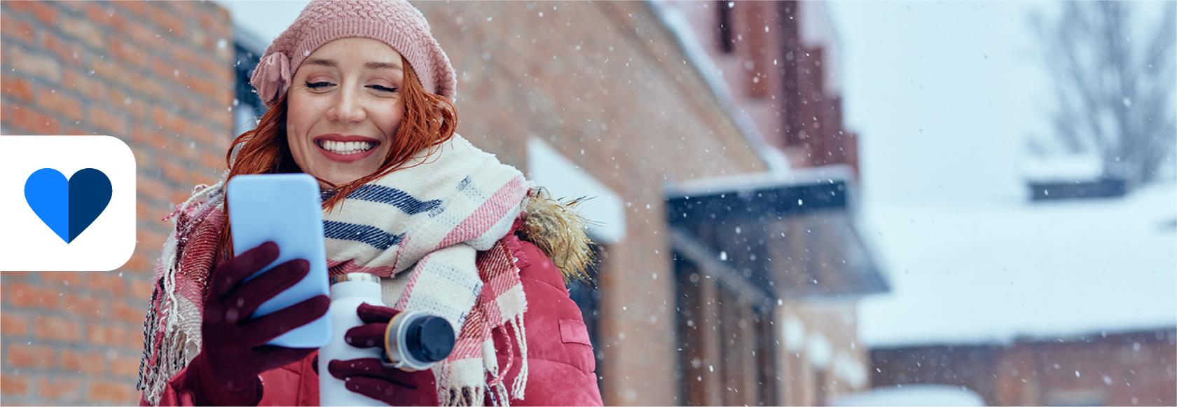 dziewczyna opatulona, w tle zima w mieście, ona z komorka