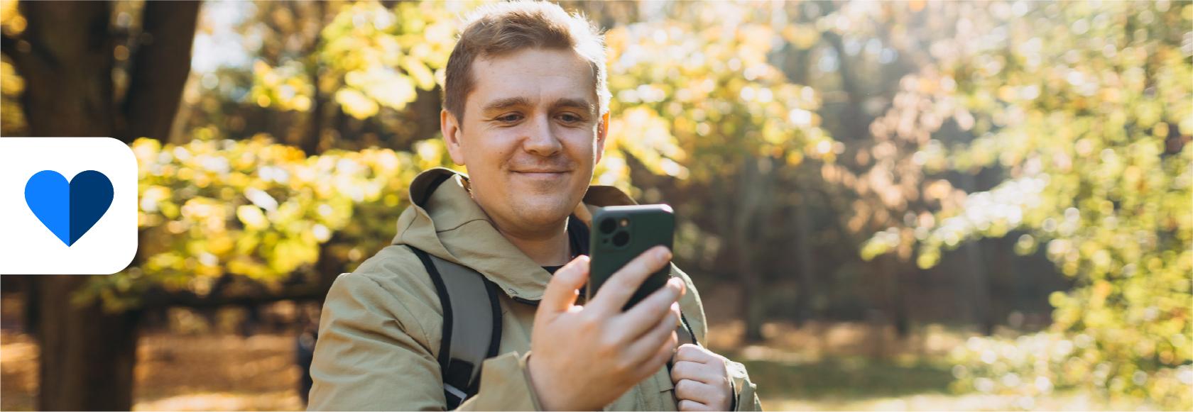 Pan przy kości na spacerze z telefonem, w tle jesienny park