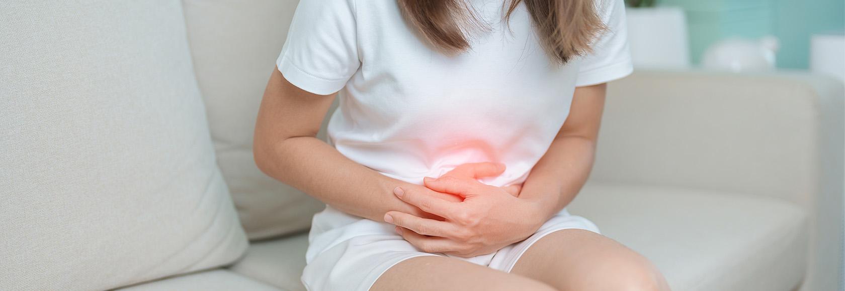 Dziewczyna siedzi i trzyma się za brzuch