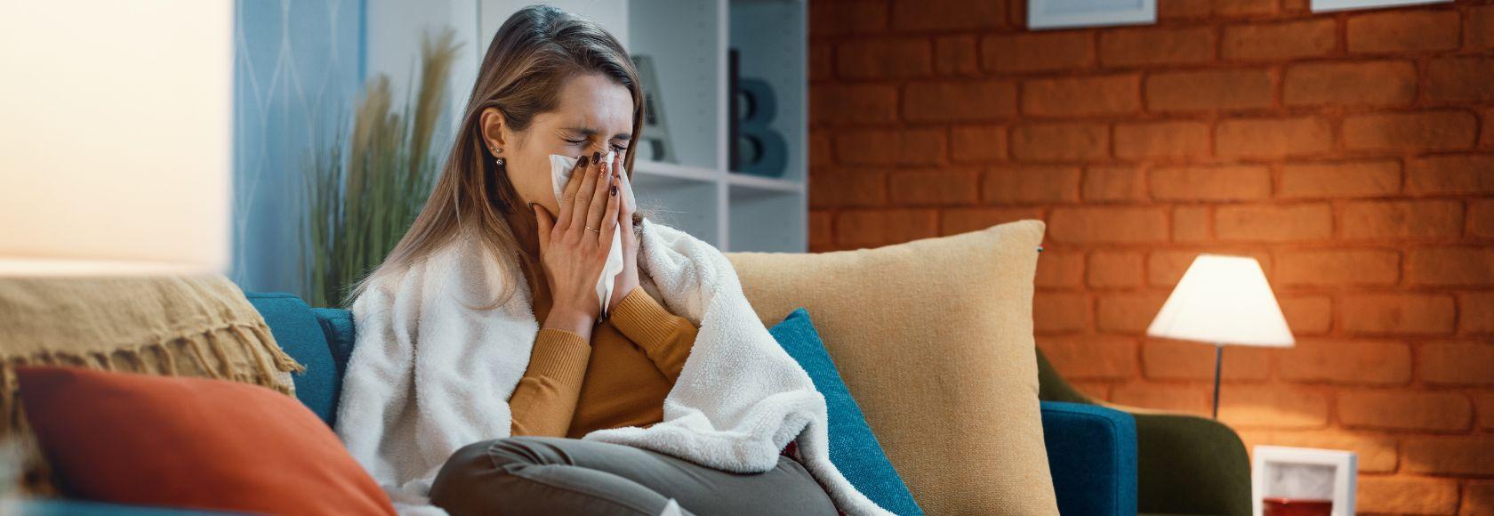 Kobieta siedzi na kanapie i wyciera nos