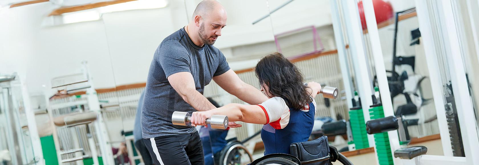 kobieta na wózku ćwiczy z fizjoterapeutą