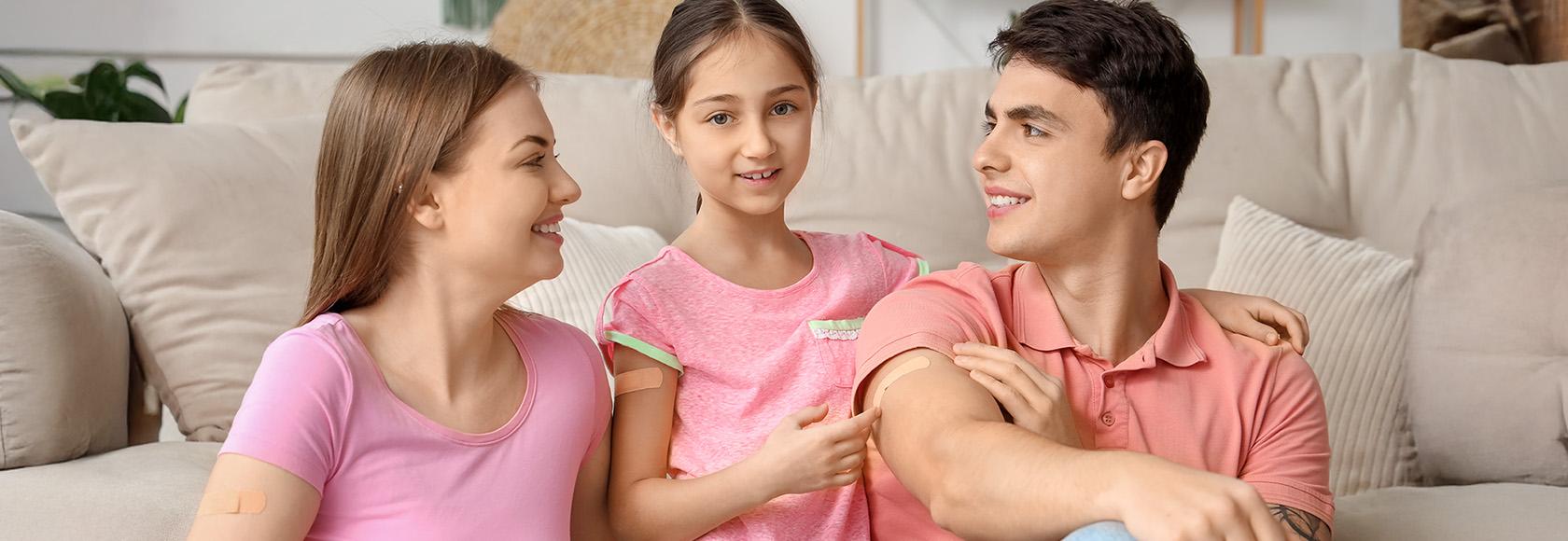 Mama, tata i córka z plastarmi po szczepieniu na ramionach