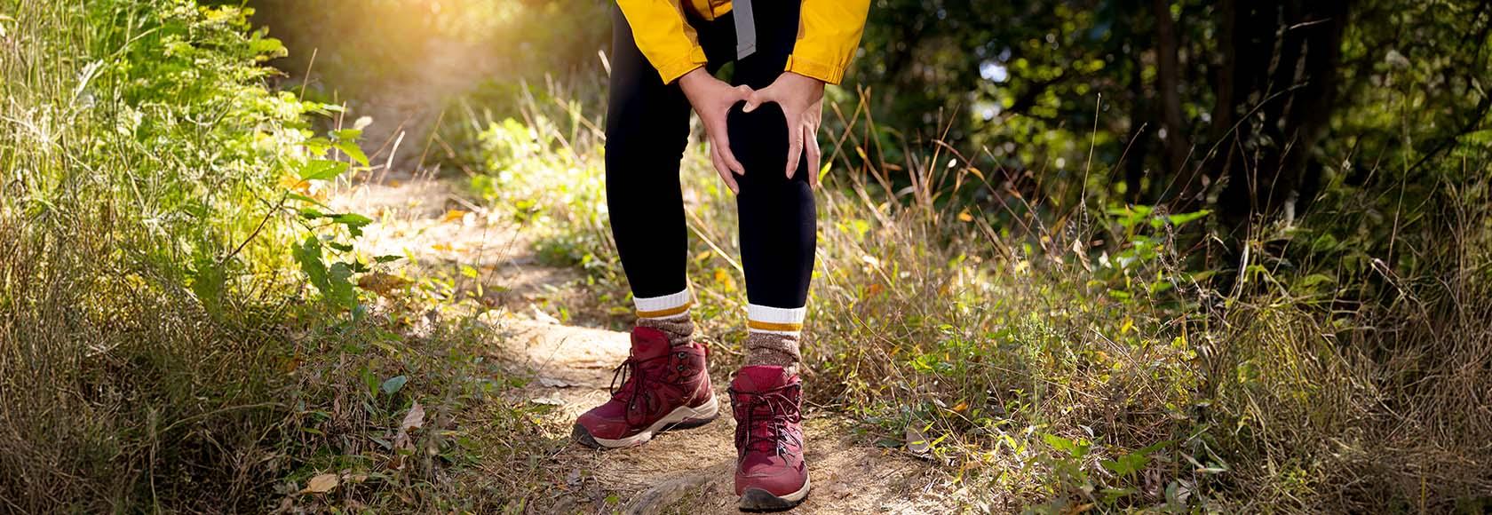 mężczyzna ubrany na sportowo chwyta się za kolano