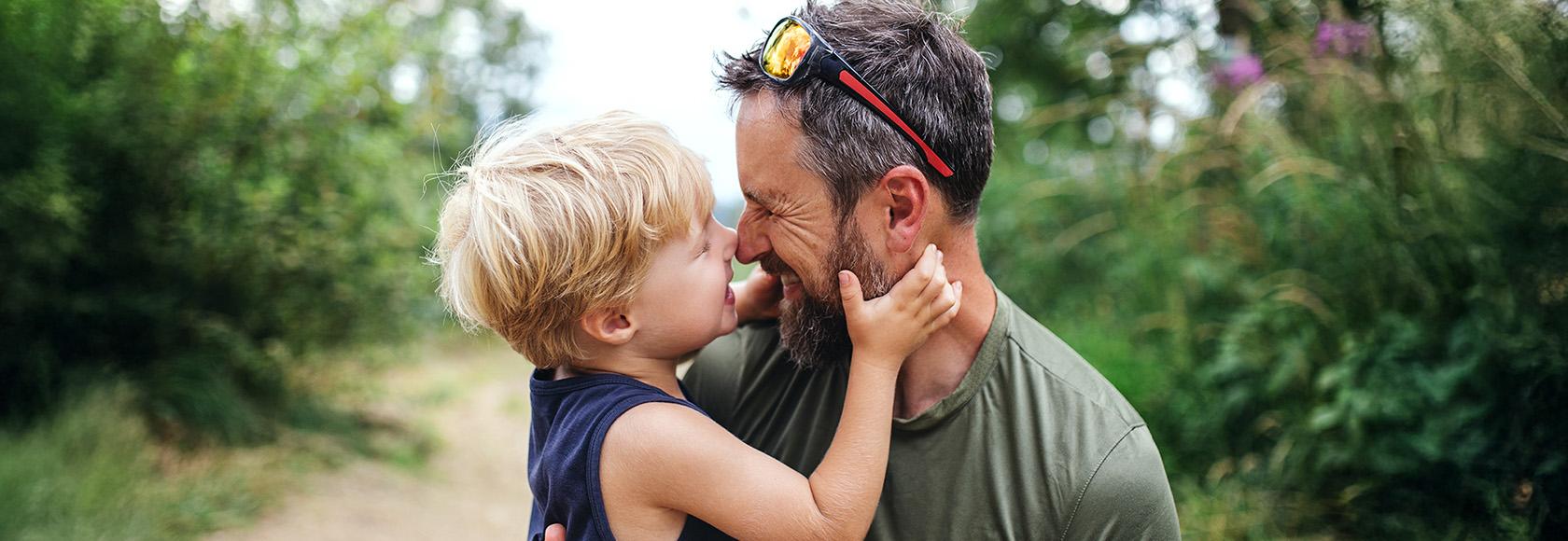 mężczyzna trzyma na rękach kilkuletniego chłopca