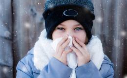 Ciepło ubrana kobieta z chusteczką przy nosie