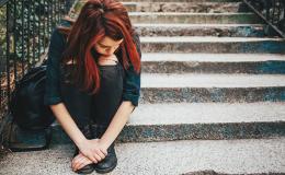 Smutna dziewczynka siedzi na kamiennych schodach