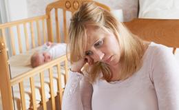 Smutna matka, w tle niemowlę w łóżeczku