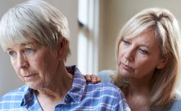 Córka kładzie rękę na ramieniu smutnej matki, starszej pani