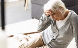 Starsza kobieta trzyma się za głowę, upadła