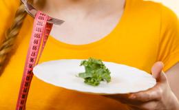 Talerz z liściem sałaty i centymetr nawinięty na widelec