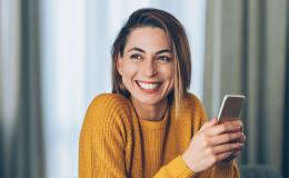 uśmiechnięta kobieta z telefonem w ręku