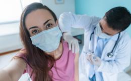 Młoda kobieta  w maseczce otrzymuje szczepionkę