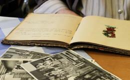 Leżące na stole lub biurku stare zdjęcia i otwarty pamiętnik. W tle zarys siedzącej osoby