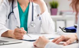 Lekarka z pacjentką siedzą przy stole. Na stole leżą dokumenty. 