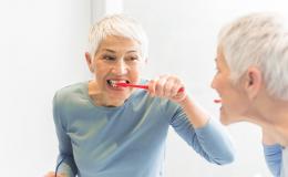 Odbicie w lustrze kobiety myjącej zęby.