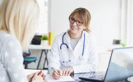 Siedząca lekarka rozmawiająca z pacjentką.