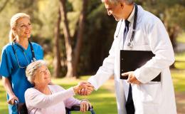 Starsza kobieta na wózku w otoczeniu lekarza i pielęgniarki