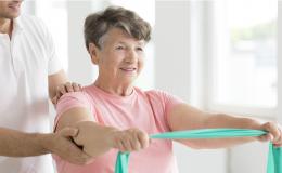 Starsza pani ćwiczy pod okiem fizjoterapeuty