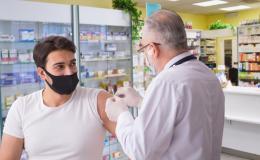młody mężczyzna jest szczepiony przez farmaceutę