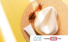 Na słomkowy kapelusz, na nim okulary i krem do opalania padają promienie słońca.