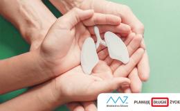 Model płuc trzymany w dłoniach, które są podtrzymywane przez większe dłonie.