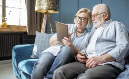 Starsza para na kanapie patrzy na tablet