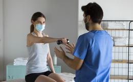 Młoda kobieta w maseczce ćwiczy z rehabilitantem