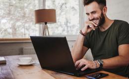 Uśmiechnięty trzydziestolatek przed komputerem