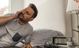 Zmęczony, zaspany mężczyzna wstaje z łóżka.