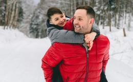 Ojciec niesie syna na barana, są w śnieżnym lesie