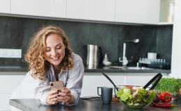 Kobieta w kuchni patrzy na telefon