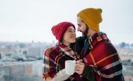 Ona w czerwonej czapce, on w żółtej, na tle mroźnego miasta otulają się kocem