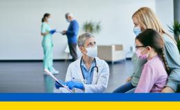 Lekarz pokazuje kartę matce z dzieckiem, flaga ukraińska na dole