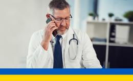 Lekarz rozmawiający przez telefon, na dole ukraińska flaga