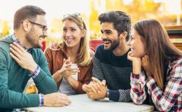 Grupa młodzieży bez maseczek rozmawia przy stole