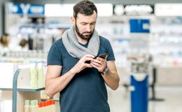 Mężczyzna w aptece patrzy na komórkę