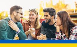 Młodzi ludzie wesoło rozmawiają przy stole, ukraińska flaga