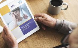 Mężczyzna trzyma w rękach tablet. Ma na nim wyświetlony poradnik dla opiekunów nad chorym na alzheimera 