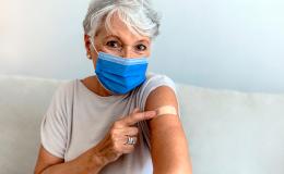 Starsza pani pokazuje, że jest po szczepieniu